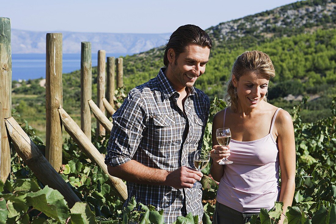 A couple with white wine in a vineyard