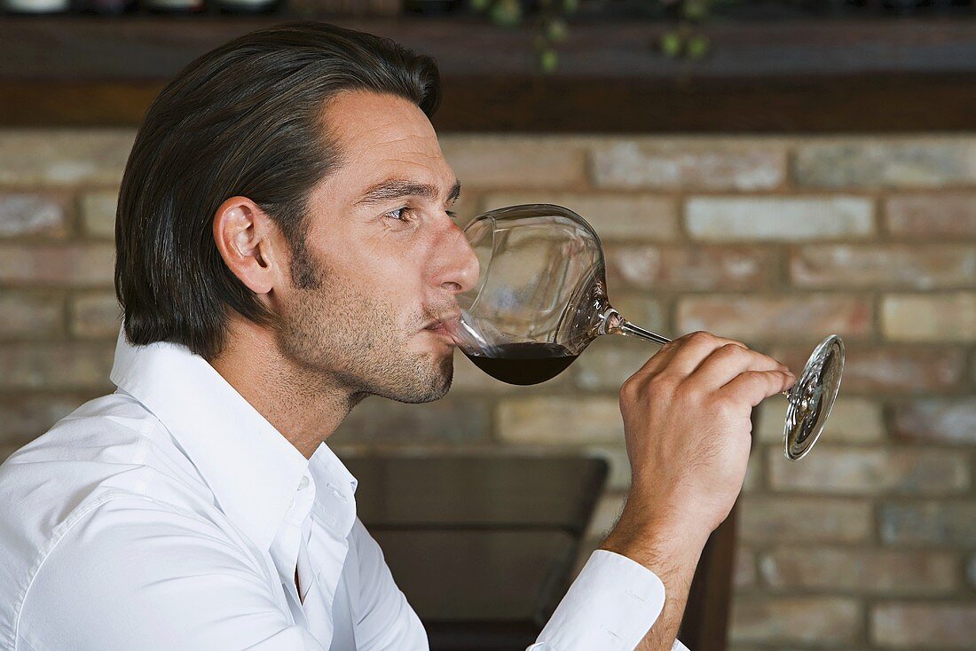 Mann testet ein Glas Rotwein