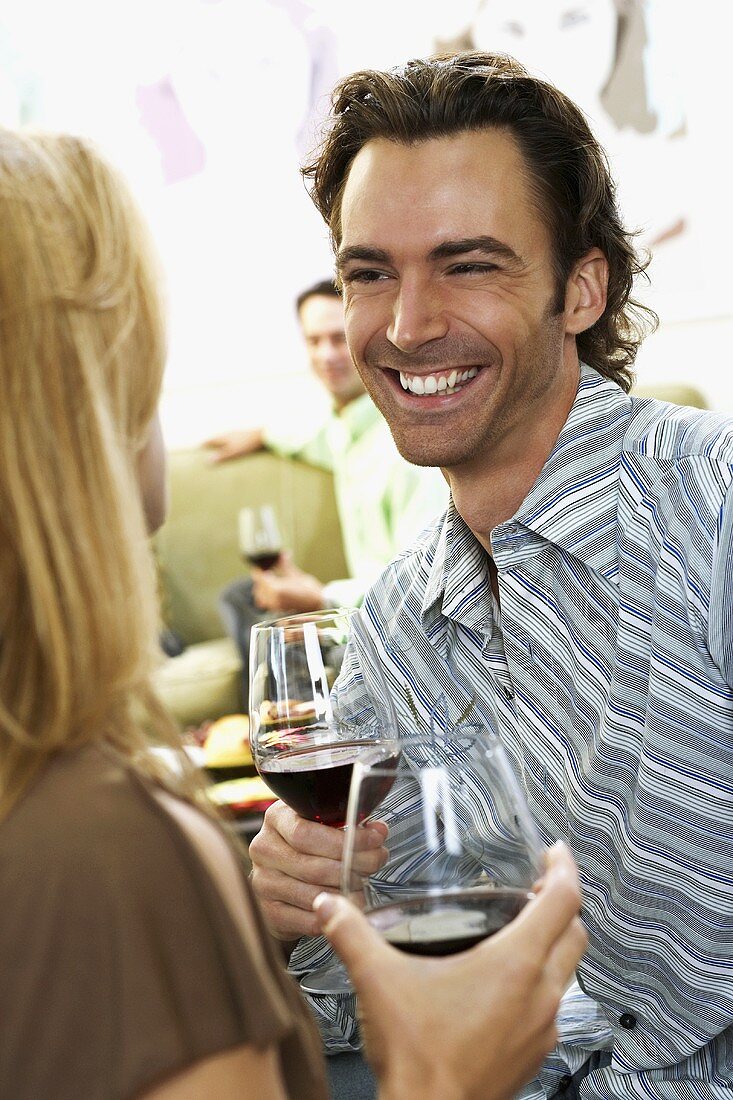 A couple at a party with glasses of red wine