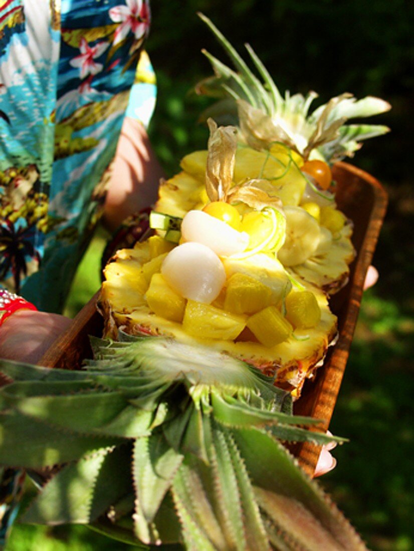 Hands holding exotic fruit salad in wooden bowl