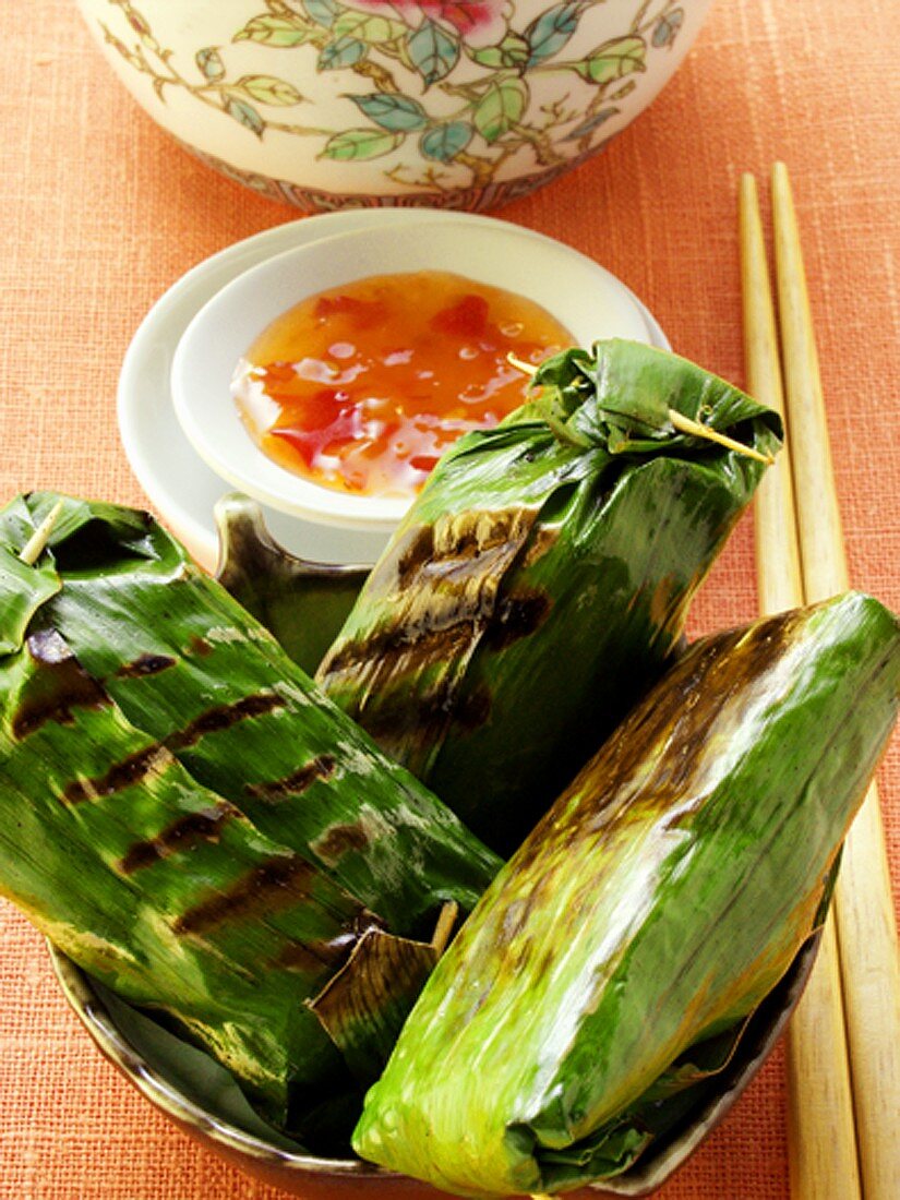 Asiatische Reispäckchen im Bananenblatt mit Chilisauce