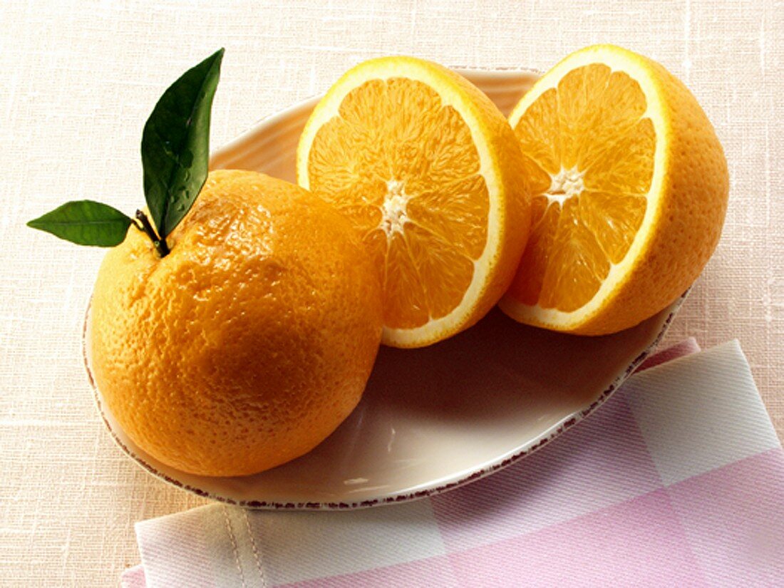 Orange und Orangenhälften auf Teller mit Serviette