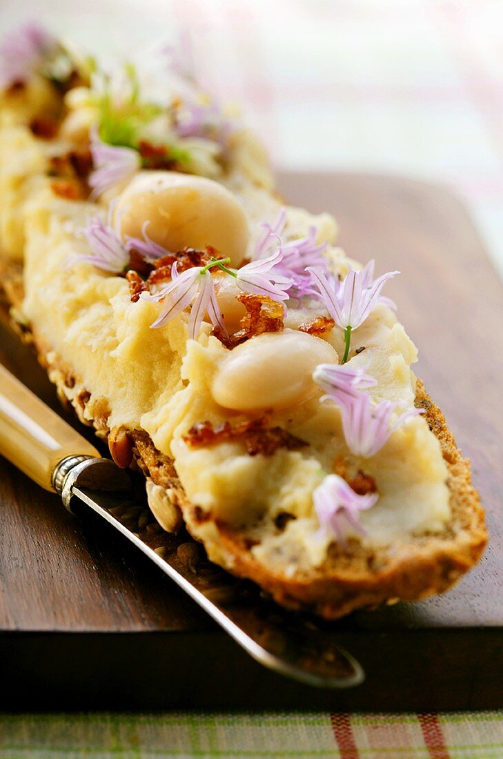 Baguette with white bean paste, bacon and edible flowers