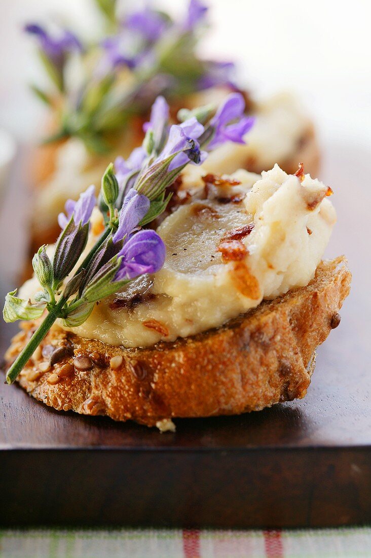 Toasted bread with white bean paste, bacon and flowers