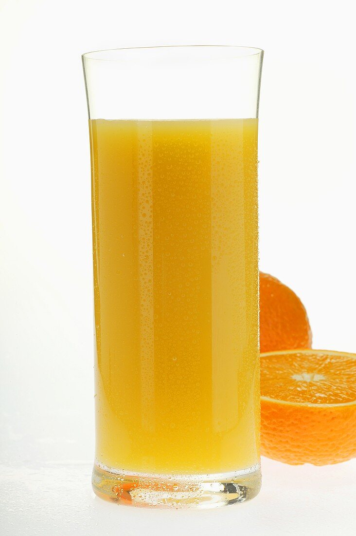 Orange juice in glass beside an orange half