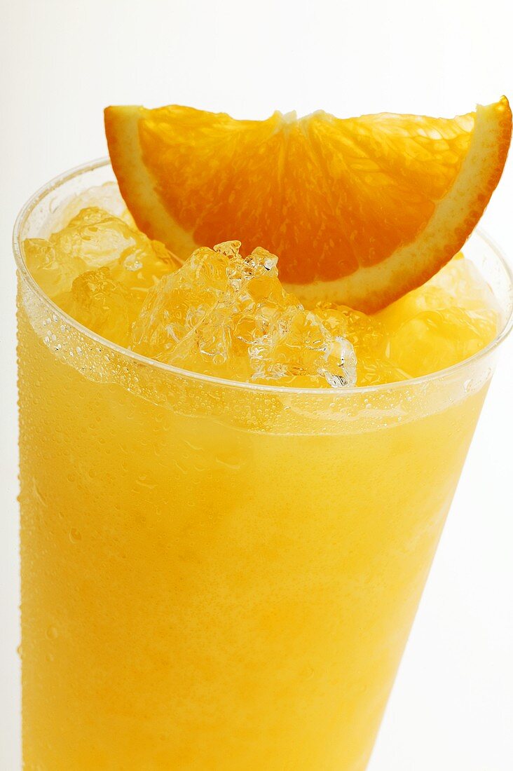 Orange juice with crushed ice and wedge of orange (close-up)