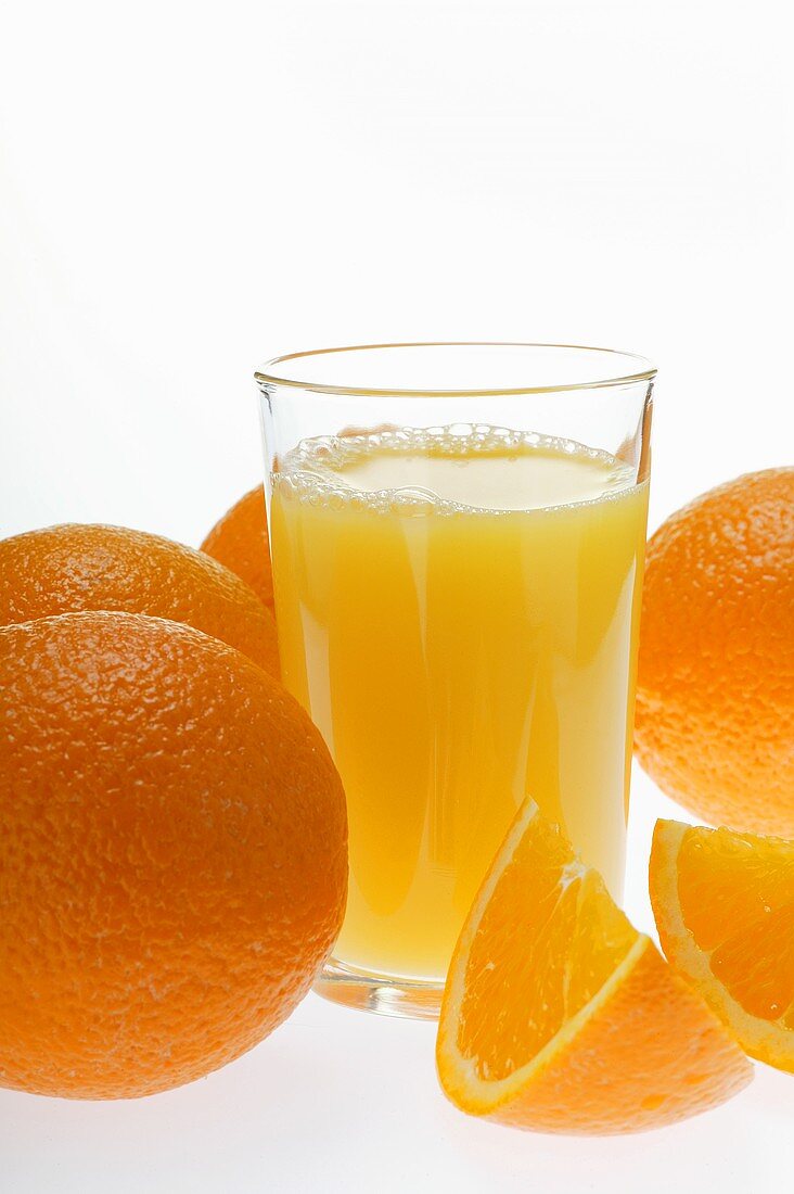 Orangensaft im Glas zwischen Orangen