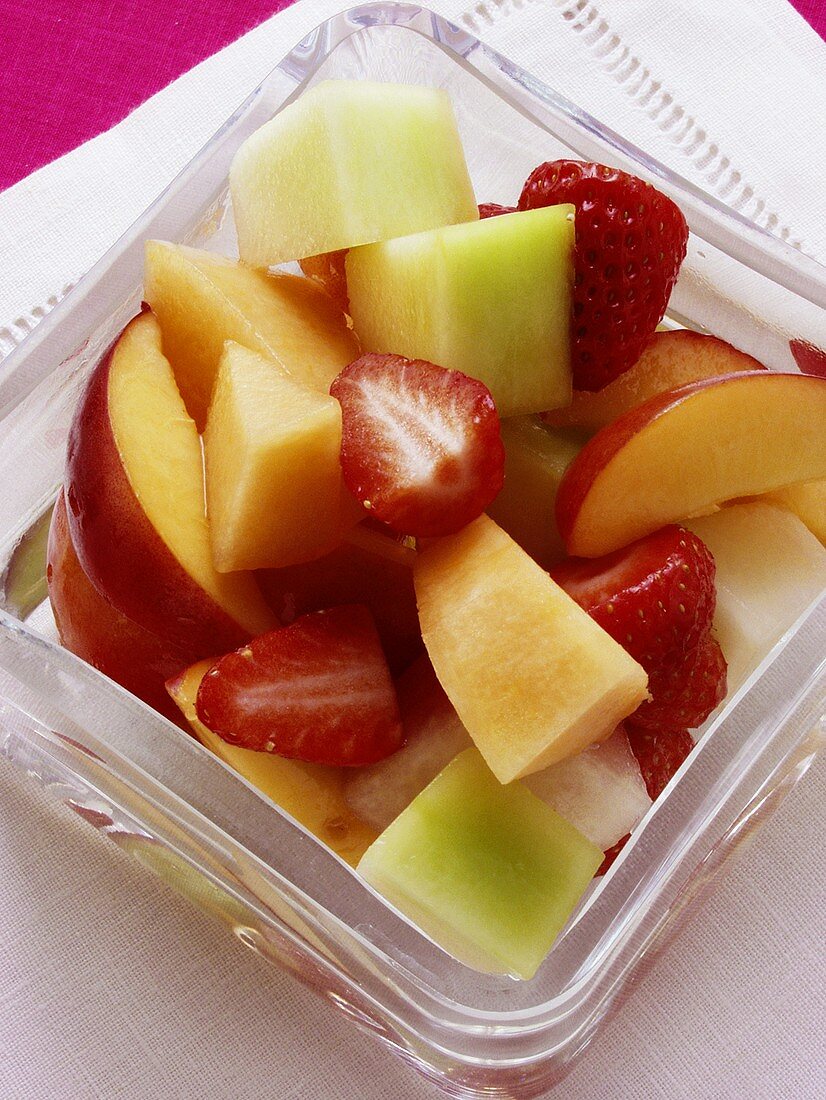 Colourful fruit salad with melon in glass bowl