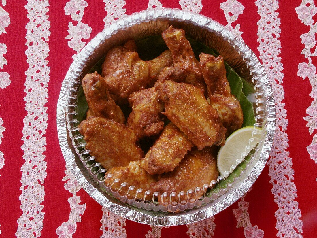 Chicken wings with wedge of lime in aluminium dish