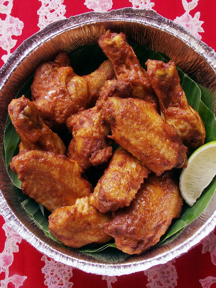 Chicken wings with wedge of lime in aluminium dish