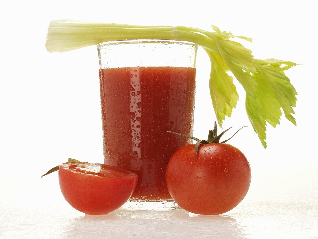Tomatensaft im Glas mit Staudensellerie; frische Tomaten