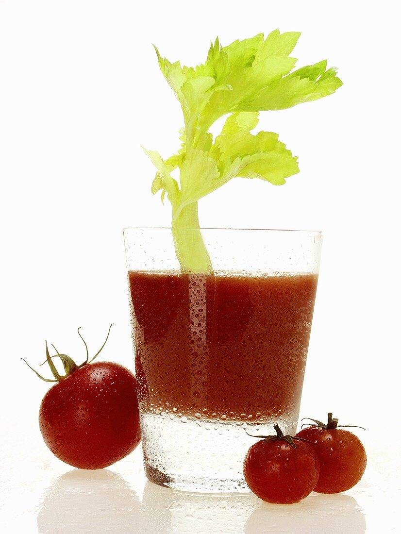 Tomatensaft im Glas mit Staudensellerie; Kirschtomaten