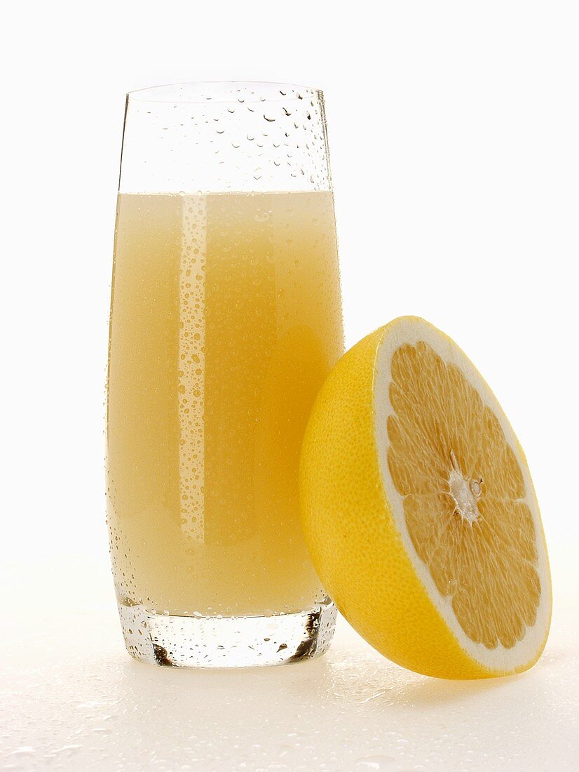 Grapefruit juice in glass beside half a grapefruit