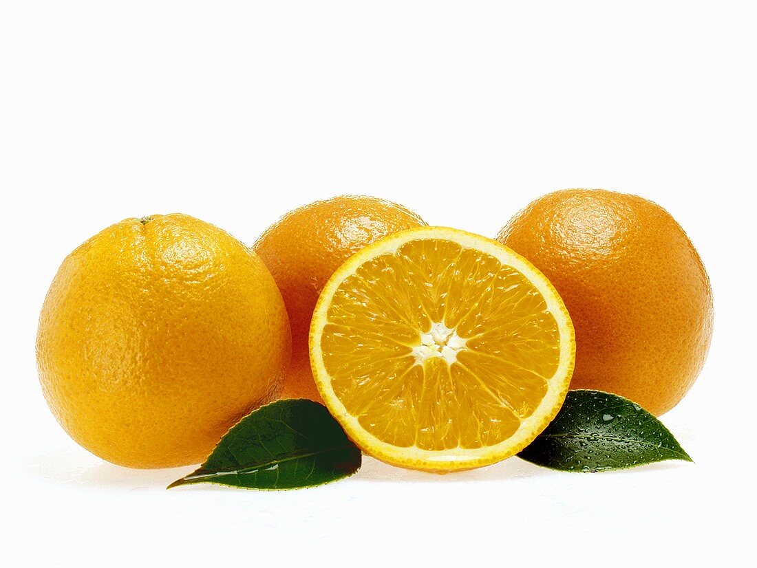 Orangen und Orangenhälfte mit Blättern und Wassertropfen