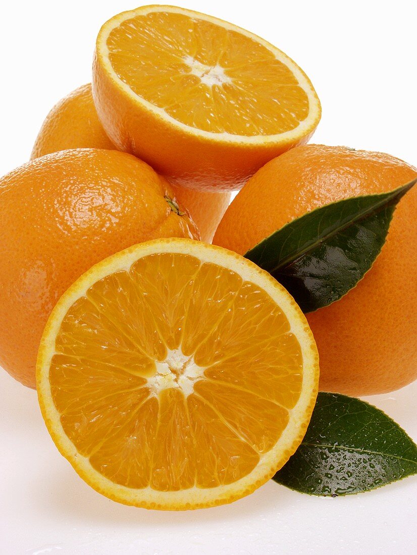 Whole and half oranges with leaves and drops of water