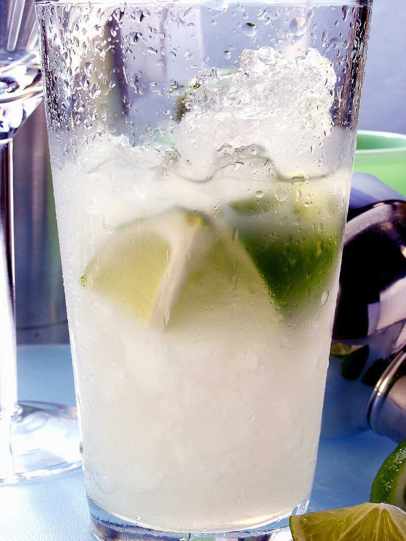 Caipirinha with ice and lime in glass; bar utensils