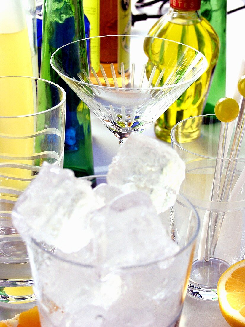 Eiswürfel im Glas, Cocktailgläser und Flaschen