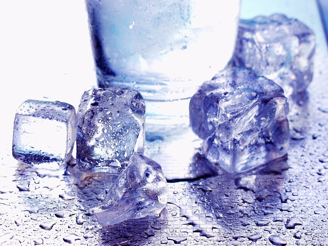Several ice cubes in front of water glass