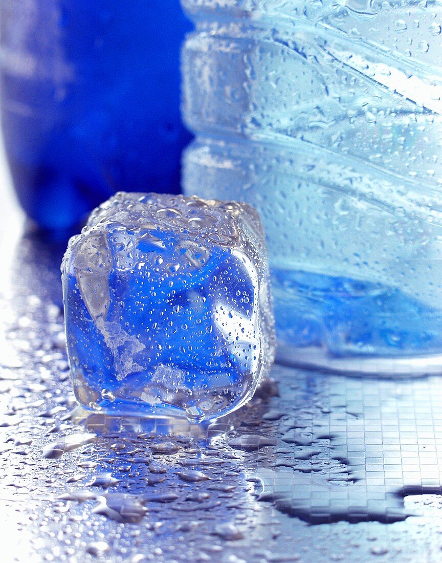 An ice cube beside a mineral water bottle