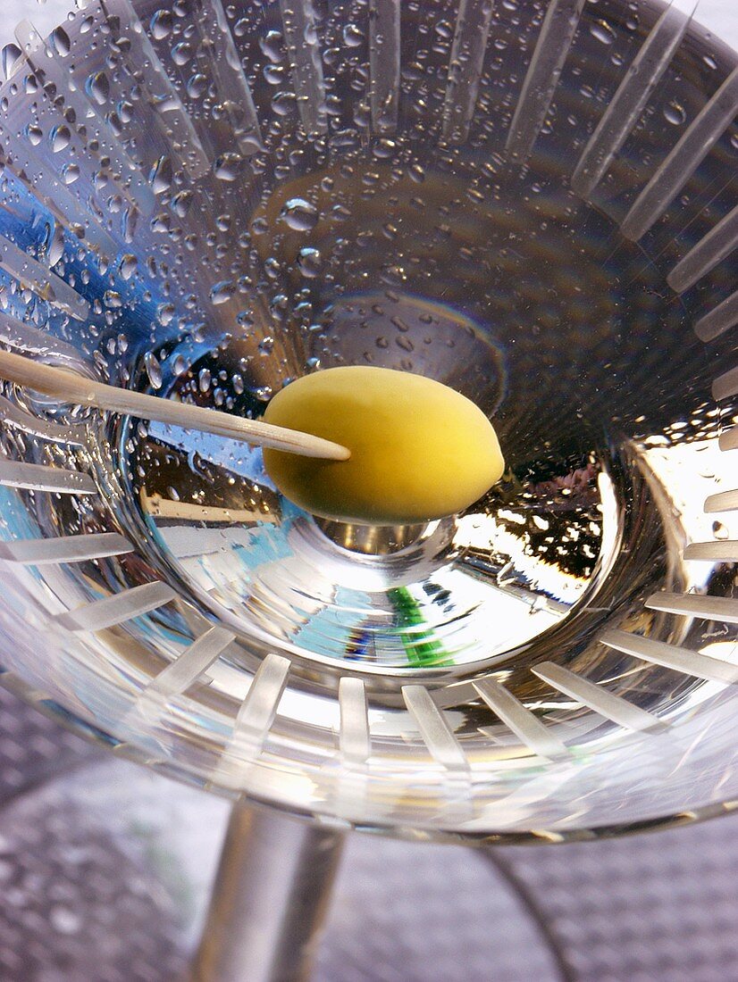 Martini with green olive on toothpick (view from above)