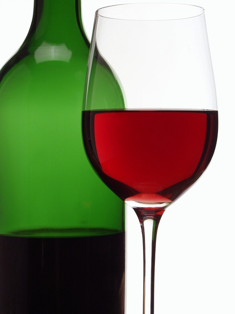 Red wine glass in front of red wine bottle