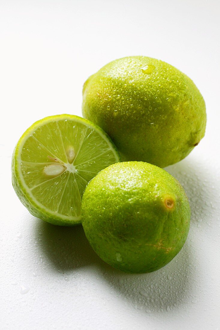Zwei Key Limes mit Wassertropfen, eine davon halbiert
