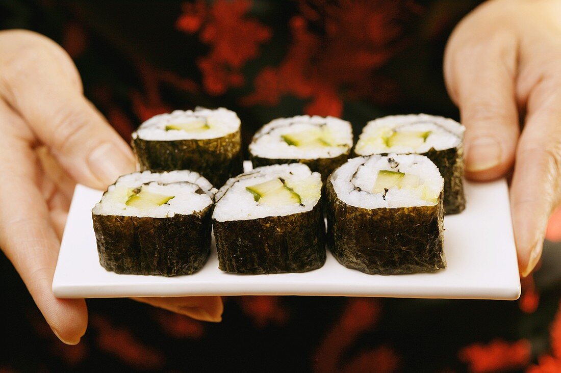 Hände servieren Maki-Sushi