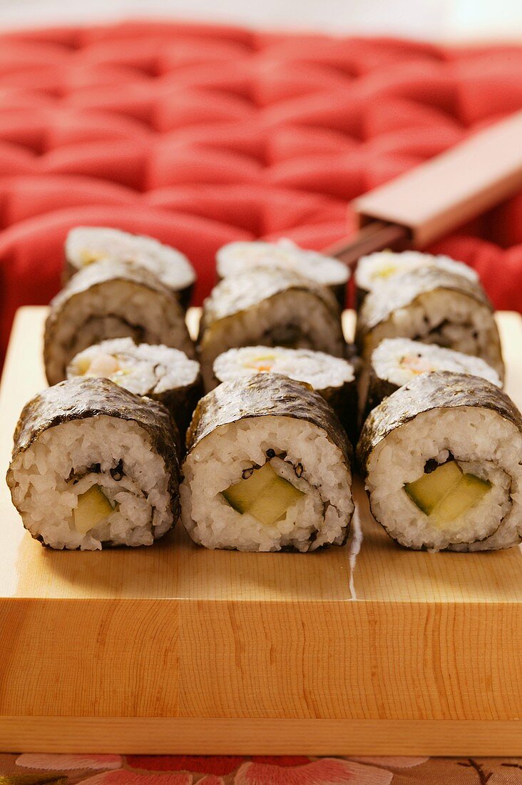 Maki-sushi platter in front of red cushion (close-up)