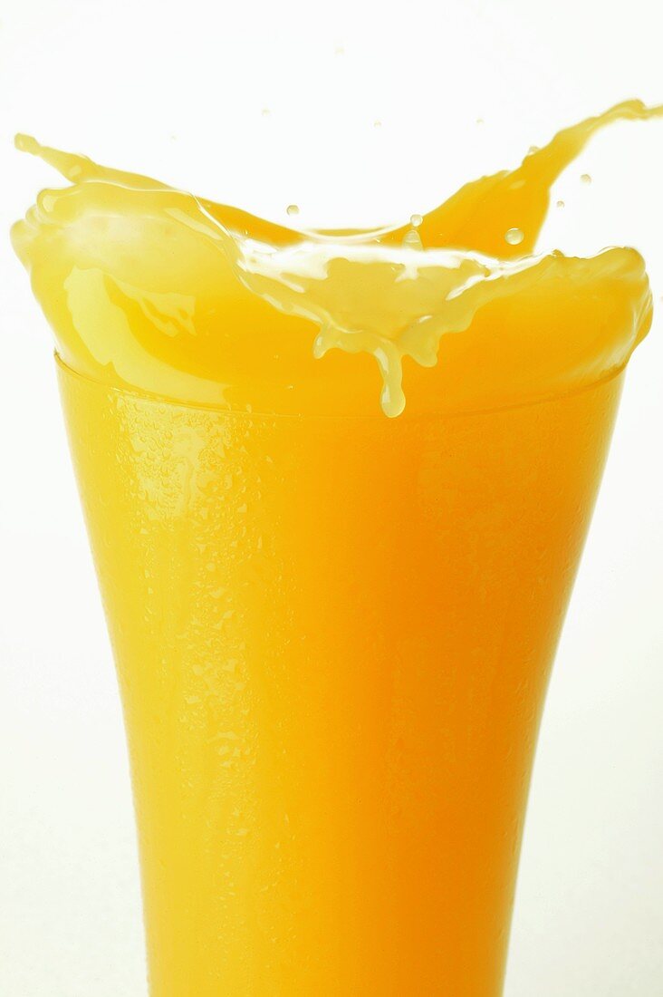 Orange juice splashing out of glass