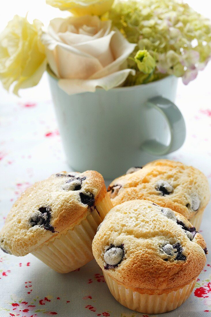 Blueberry muffins in front of bouquet of flowers