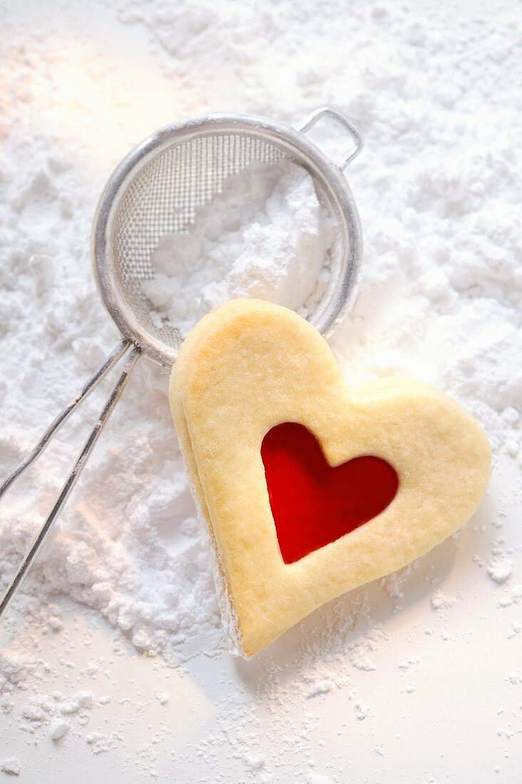 Sweet pastry heart with raspberry jam on icing sugar