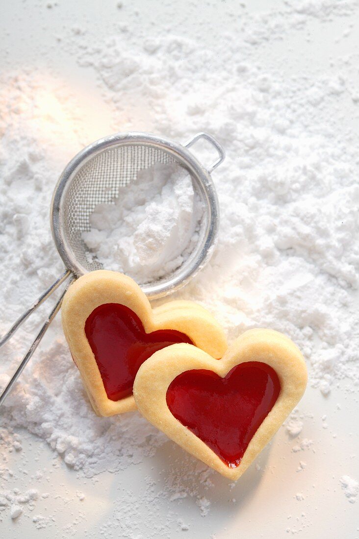 Sweet pastry hearts with raspberry jam on icing sugar