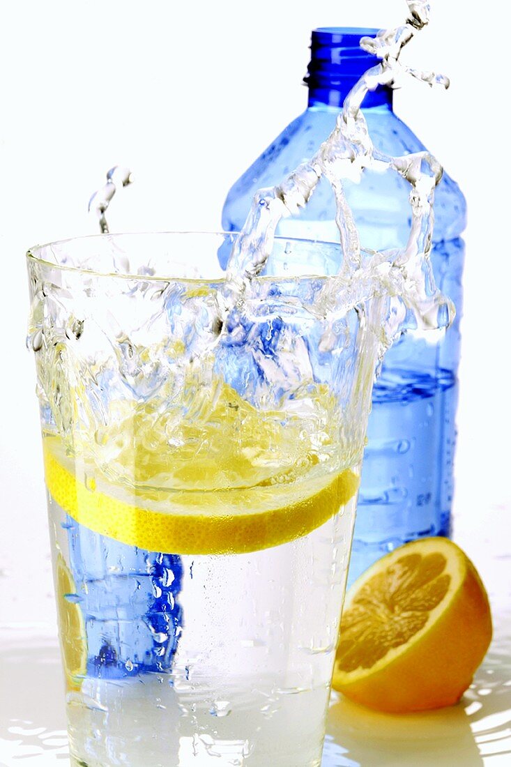 Slice of lemon falling into a glass of mineral water