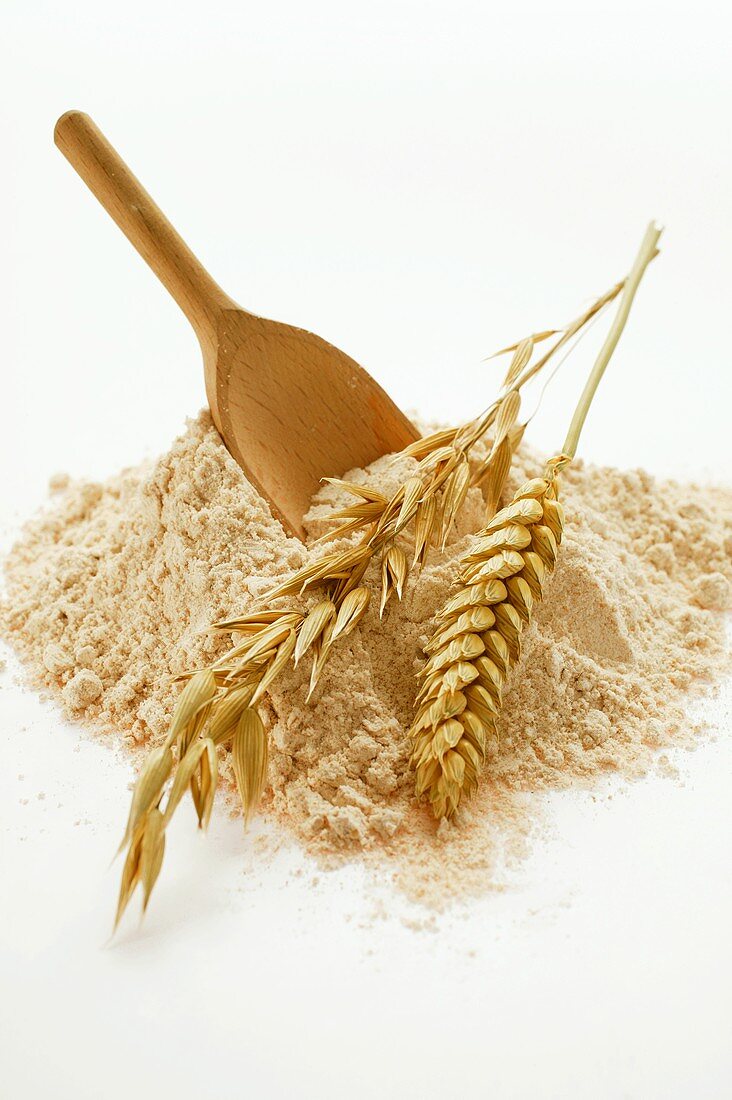 Wholemeal flour with wooden scoop and cereal ears