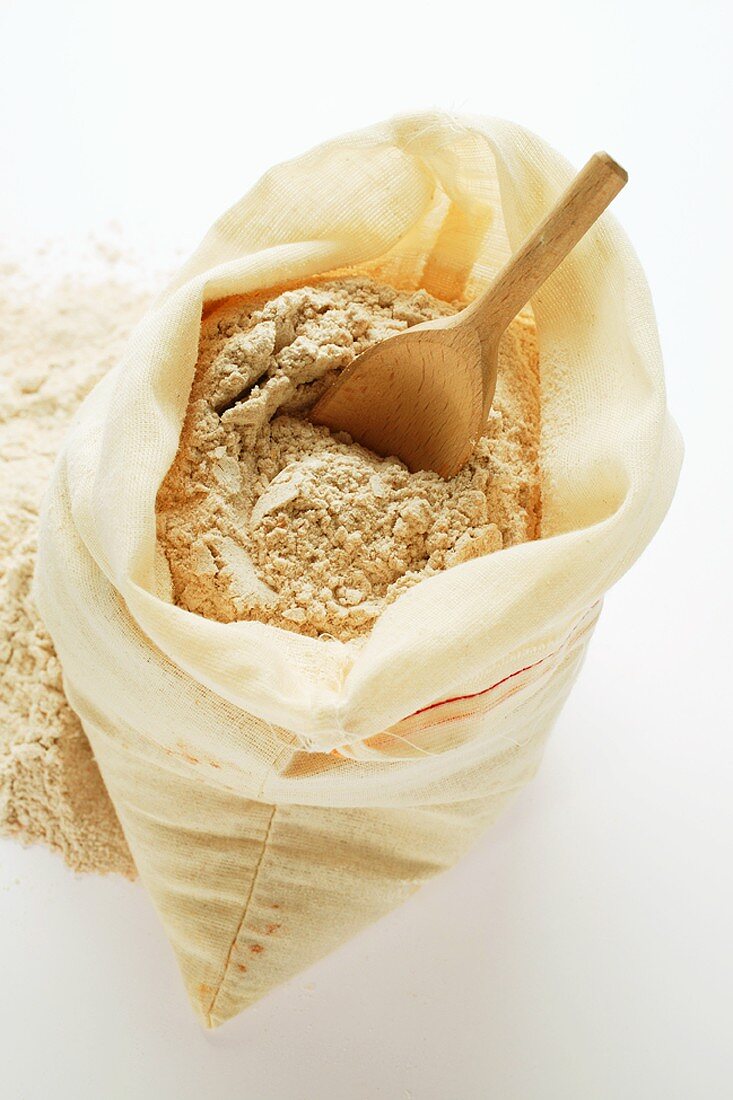 Wholemeal flour in sack with wooden scoop