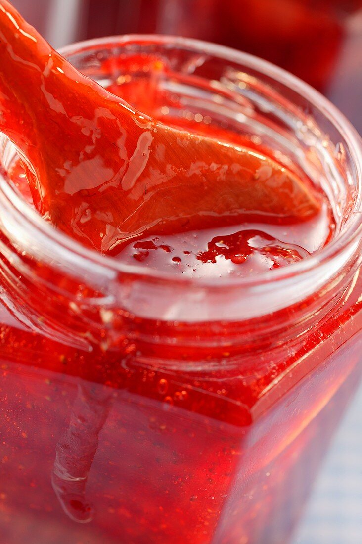 Strawberry jam in jar with wooden spoon