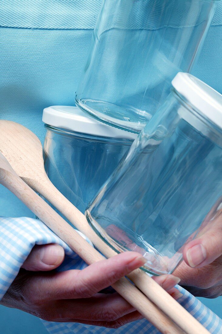 Woman holding jam jars and kitchen spoon