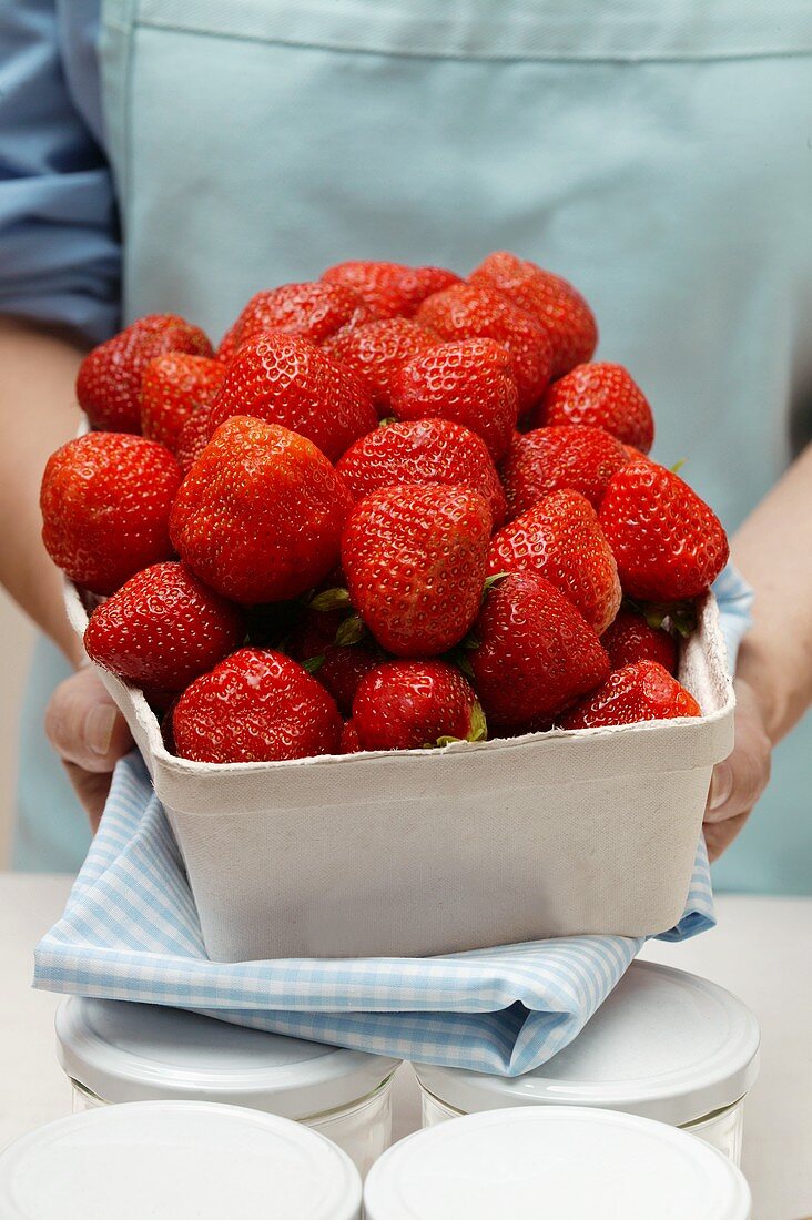 Frau hält Schale Erdbeeren; Einmachgläser