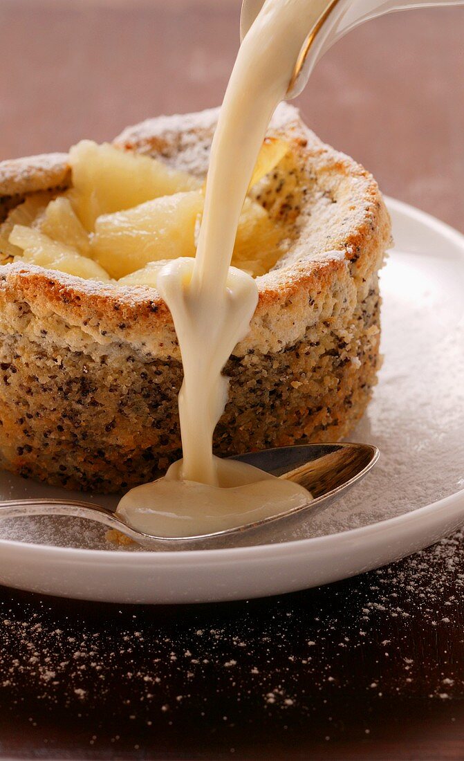 Pouring custard over pineapple and poppy seed soufflé