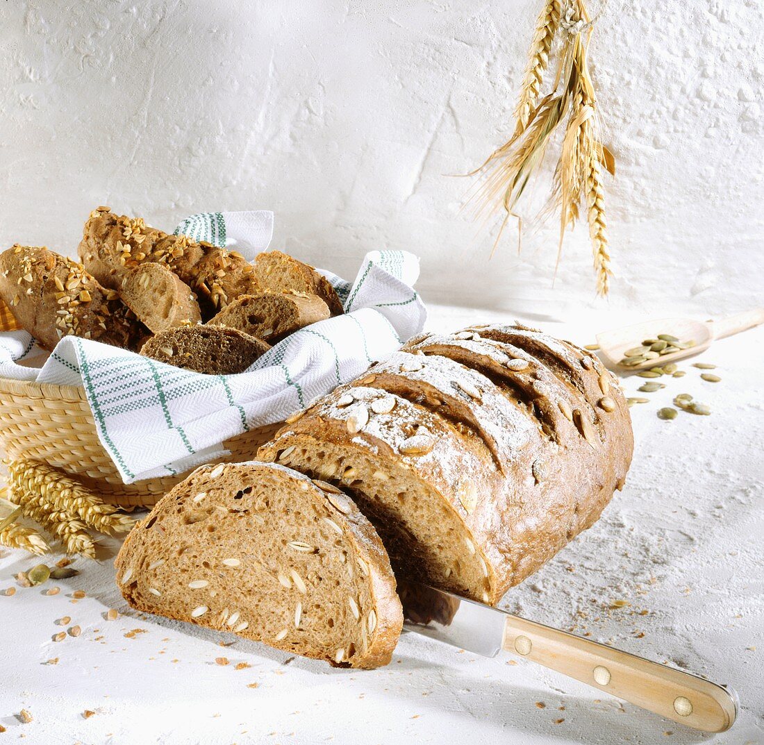 Sunflower seed bread, a slice cut; bread rolls in bread basket