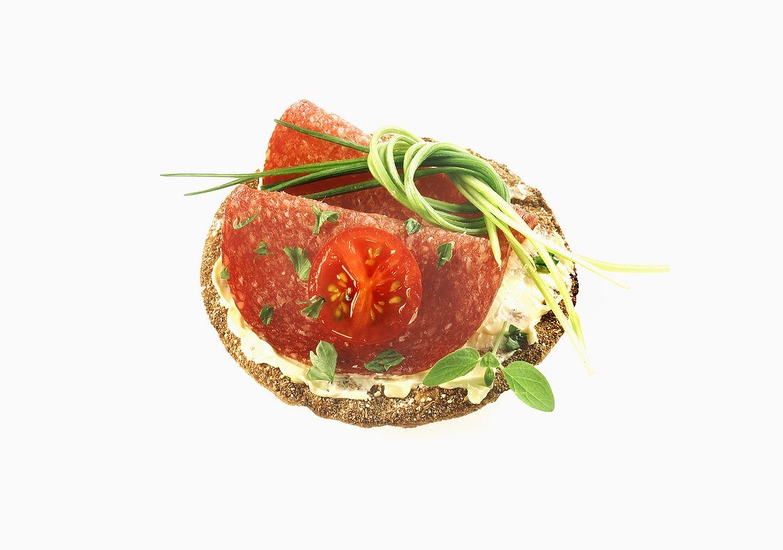 Cracker with salami, tomato and herbs