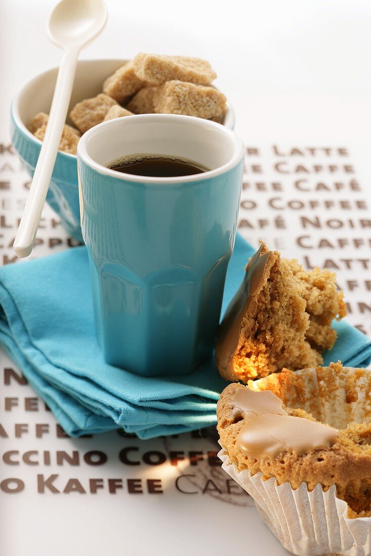 Blaue Espressotasse, Muffin und braune Zuckerwürfel