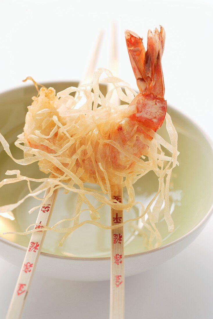 King prawn, fried in rice noodles, on chopsticks