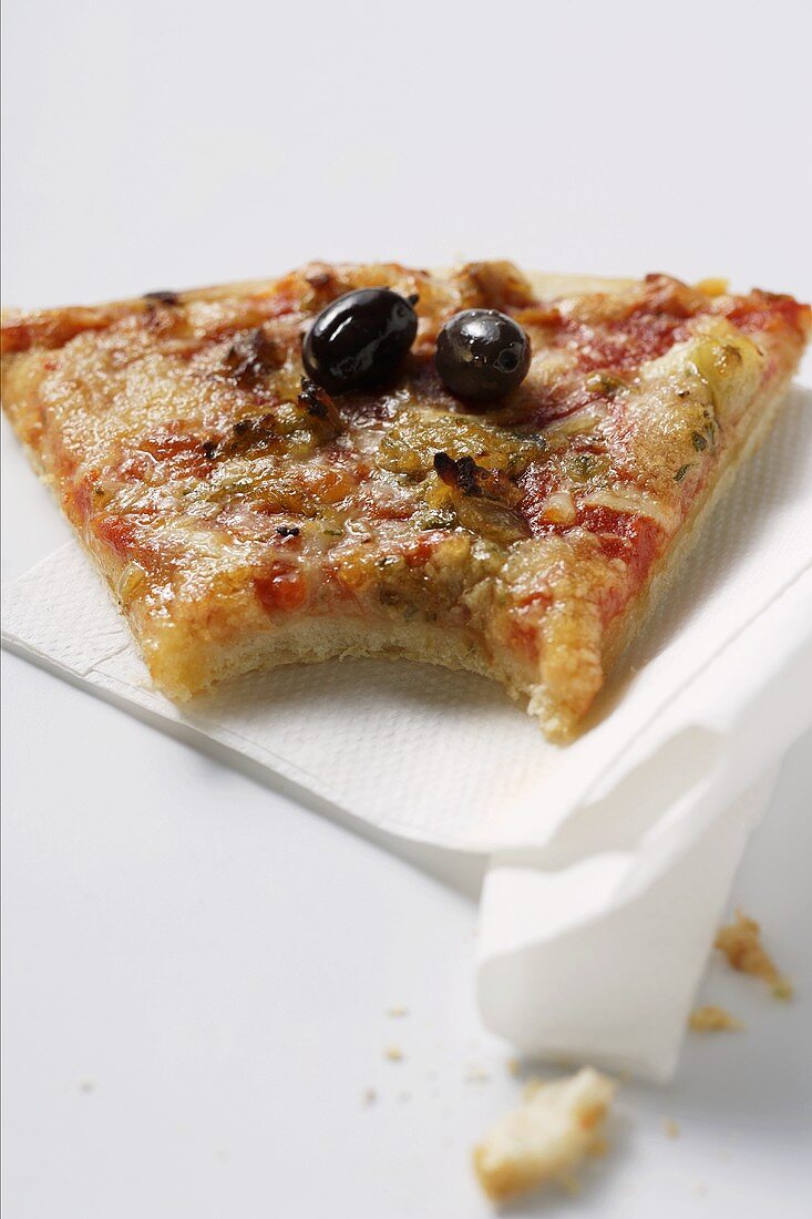 Angebissenes Stück Pizza mit Thunfisch und Oliven