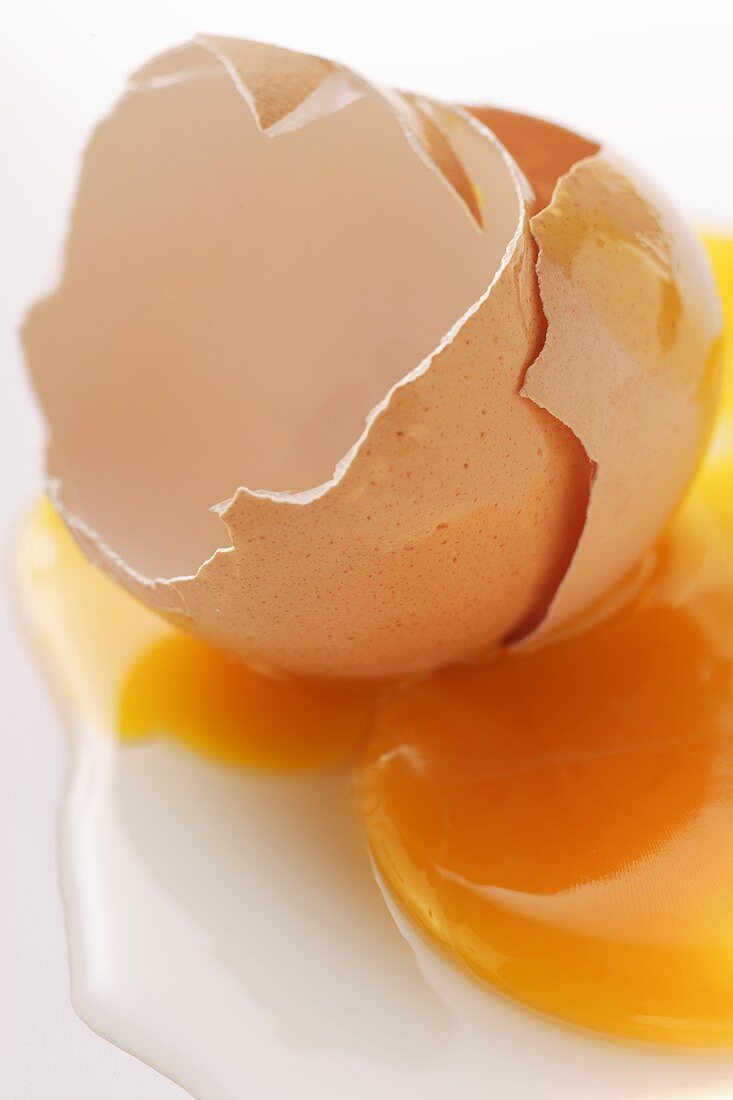 Egg yolk and eggshells on white background
