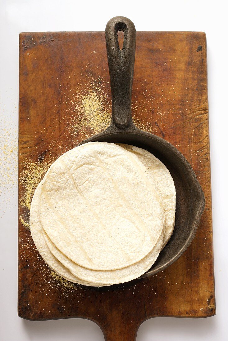 Wheat tortillas in frying pan on chopping board