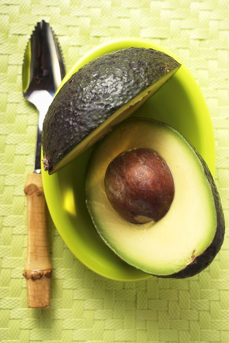 Avocado, halbiert, auf grünem Teller