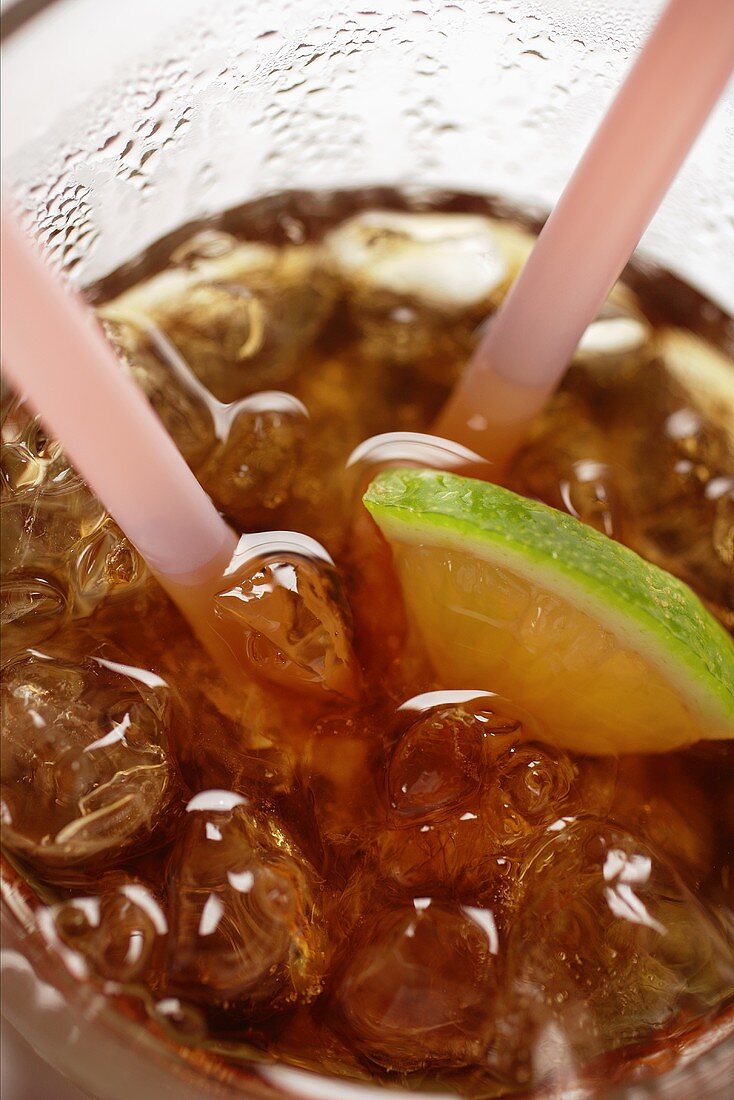 Cola with ice cubes and lemon (close-up)