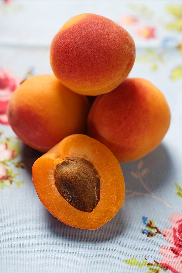 Apricots, one halved, on floral tablecloth