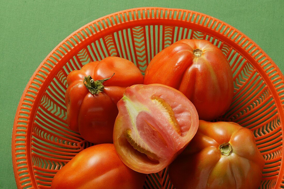 Fresh tomatoes in red bowl (close-up)